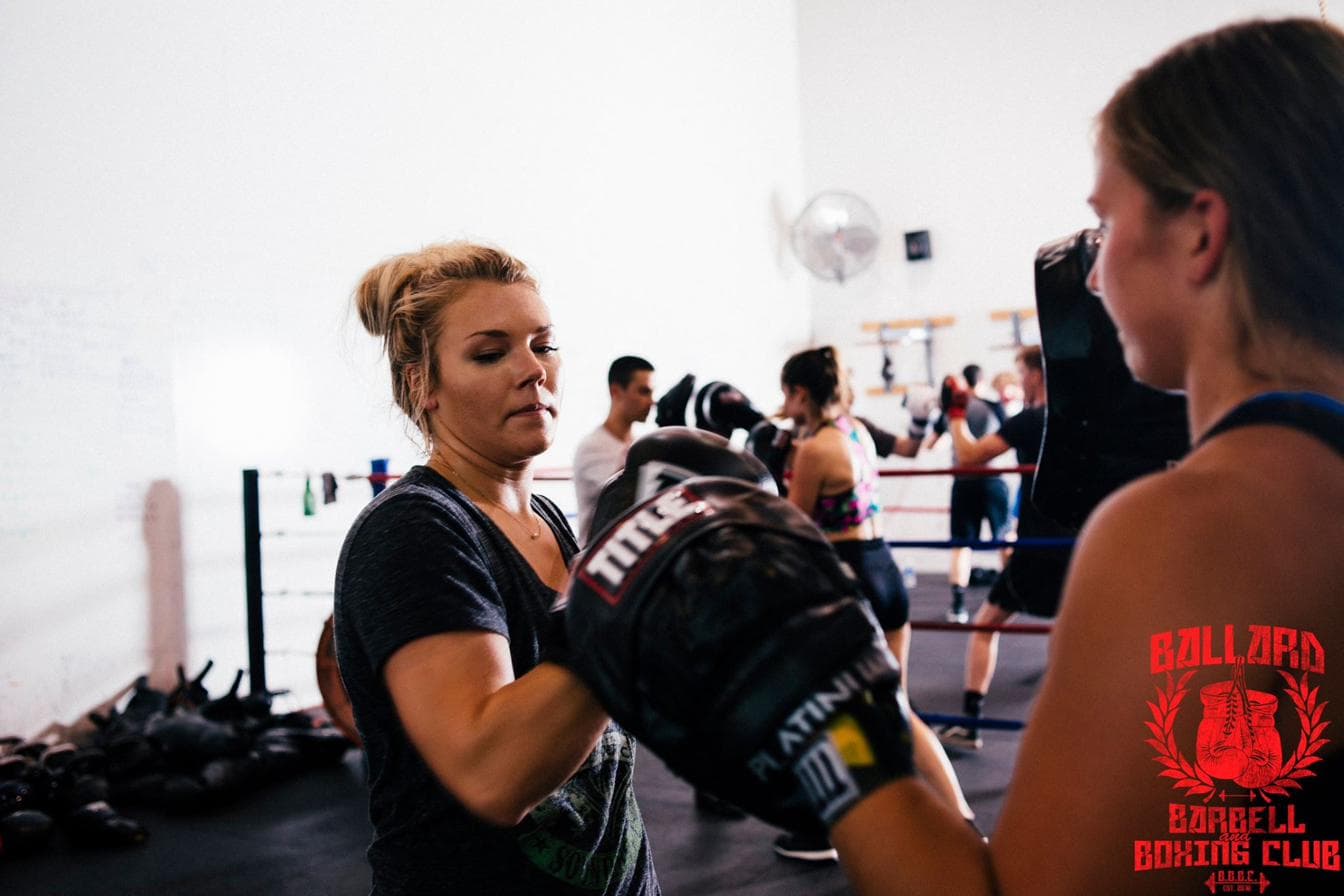 A coach holding focus mitts for a member during a Parkinson's boxing class at BBBC