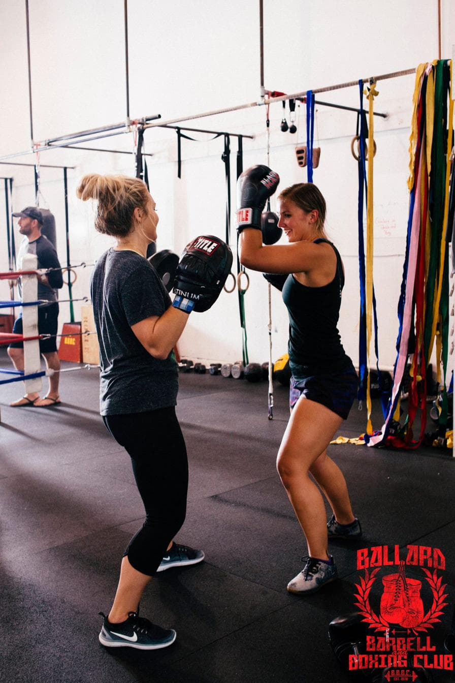 Two members working mitts and laughing at Ballard Barbell and Boxing Club